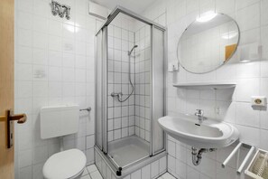 A modern bathroom with a glass-enclosed shower, a white toilet, and a sink with a mirror above it. - Havenu Oberkochen-Mitte - Doppelzimmer (Oberkochen)
