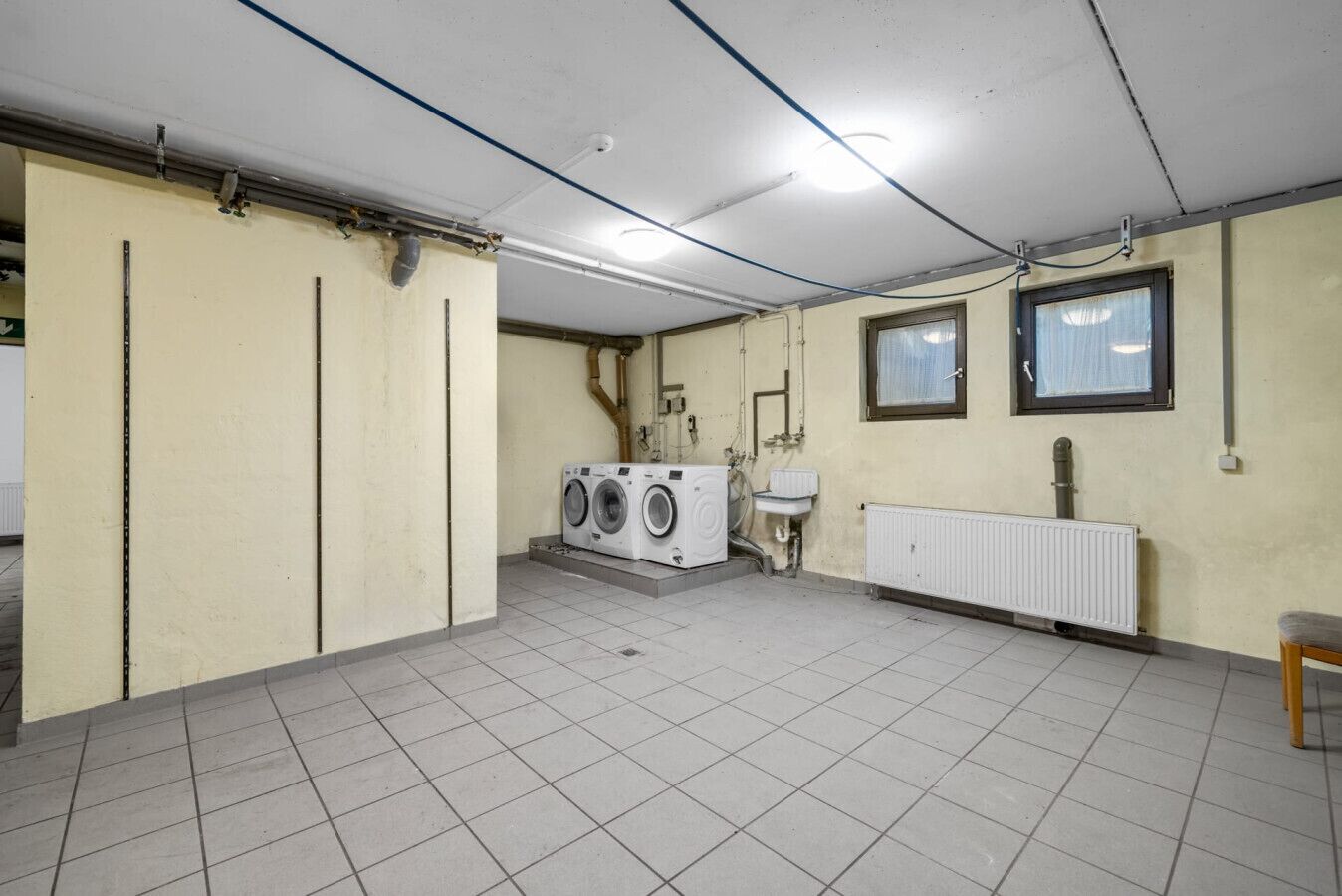 A laundry room with a washing machine, a sink, and a radiator.
