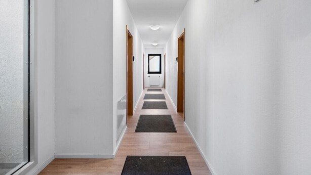 A modern, narrow hallway with wooden flooring and white walls. - Havenu Oberkochen-Mitte - Doppelzimmer (Oberkochen)