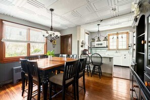 A dining area with a wooden table and chairs, a chandelier, and a view of the kitchen. - Center House 1901 | Walk to Broadway | Parking (Jim Thorpe)