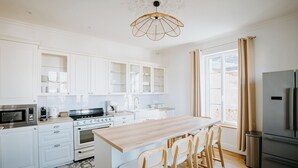 Una cocina moderna con armarios blancos, una isla de madera y un refrigerador de acero inoxidable.