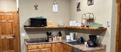 A kitchen with wooden cabinets, a granite countertop, a ceiling fan, and a trash can.
