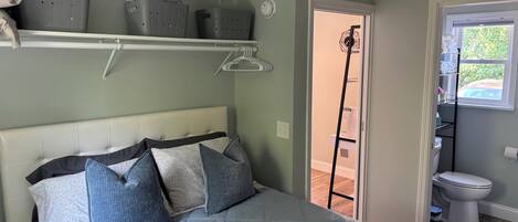 A bedroom with a bed, a ceiling fan, a window, and a door leading to a bathroom.