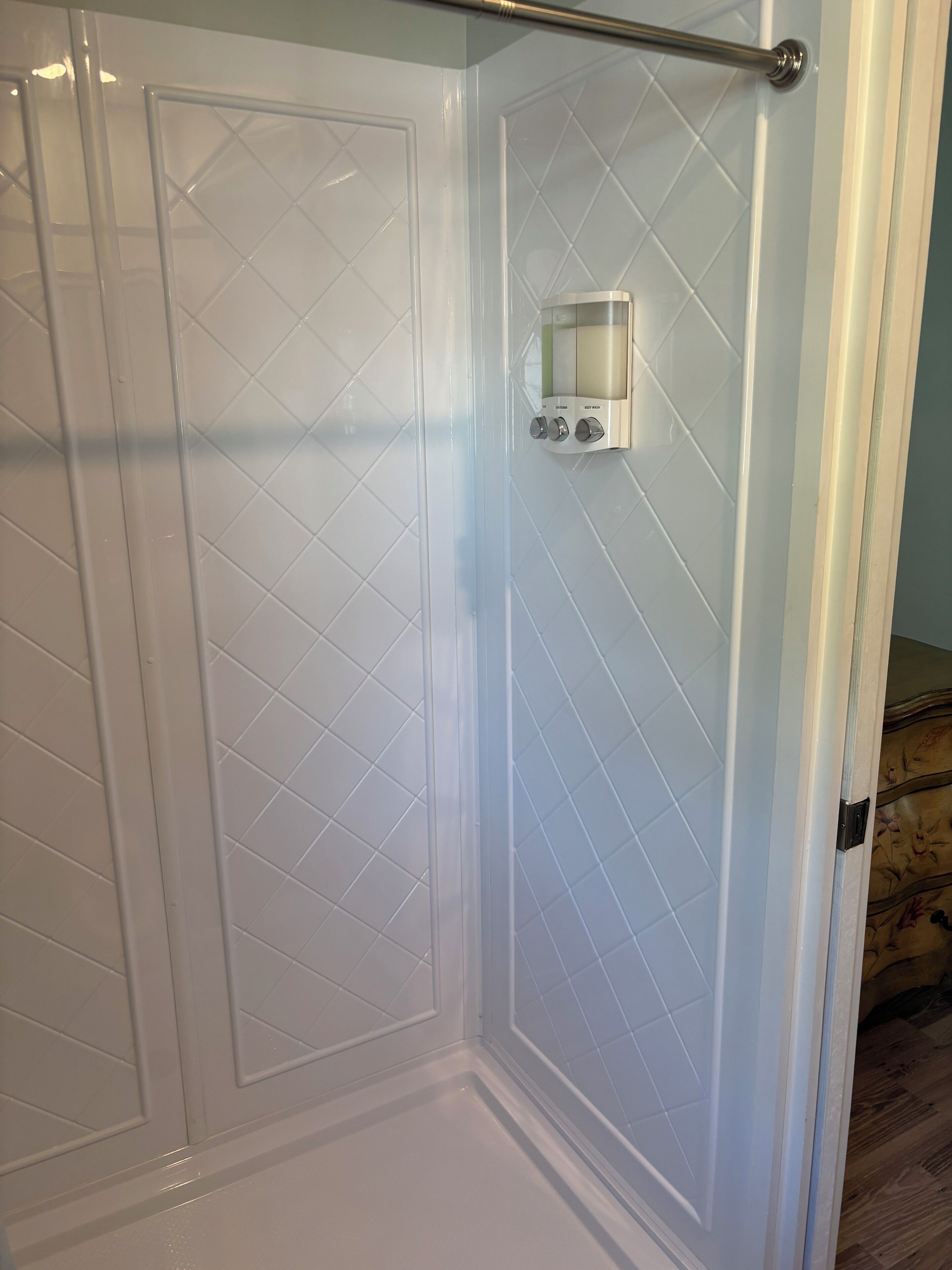 A bathroom with white tiled walls, a shower area, and a towel rack.
