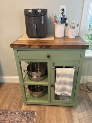 A kitchen island with a built-in oven, two stainless steel bowls, a hanging towel, and a utensil holder.