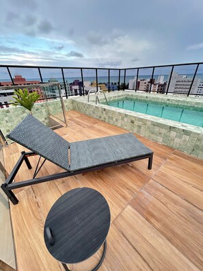 A rooftop pool area with a lounge chair and a small table. - Melhores Flats - Surreal (Cabedelo)