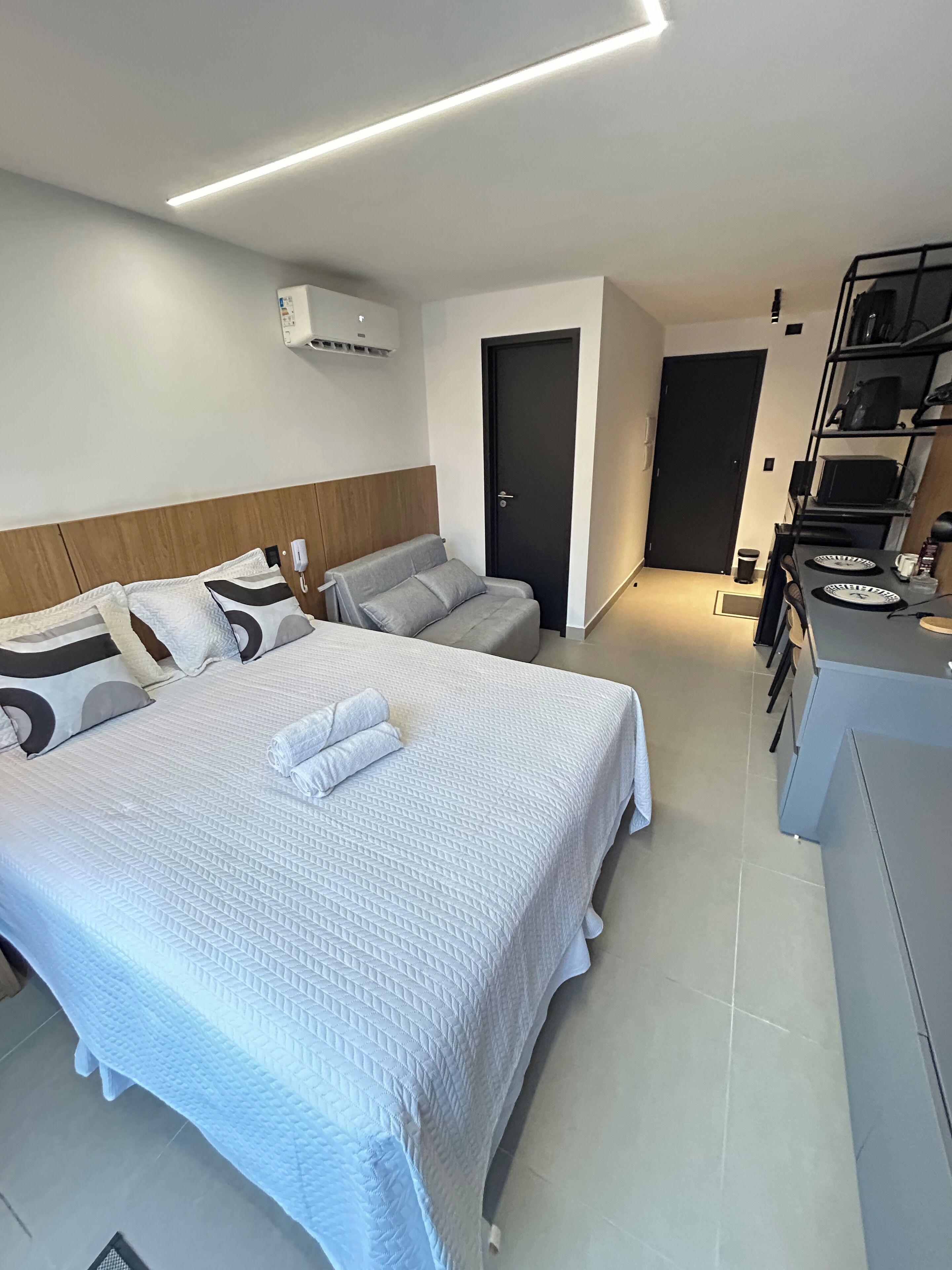 A modern hotel room with a large bed, a smaller bed, a desk, and a wardrobe.