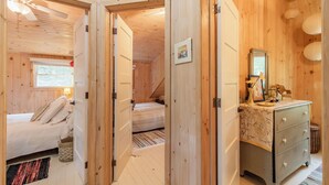 A cozy wooden room with a bed, a dresser, and a mirror. - Walk to white sand private beach of Oakwood Park - 4 bed cottage steps to lake. (Grand Bend)