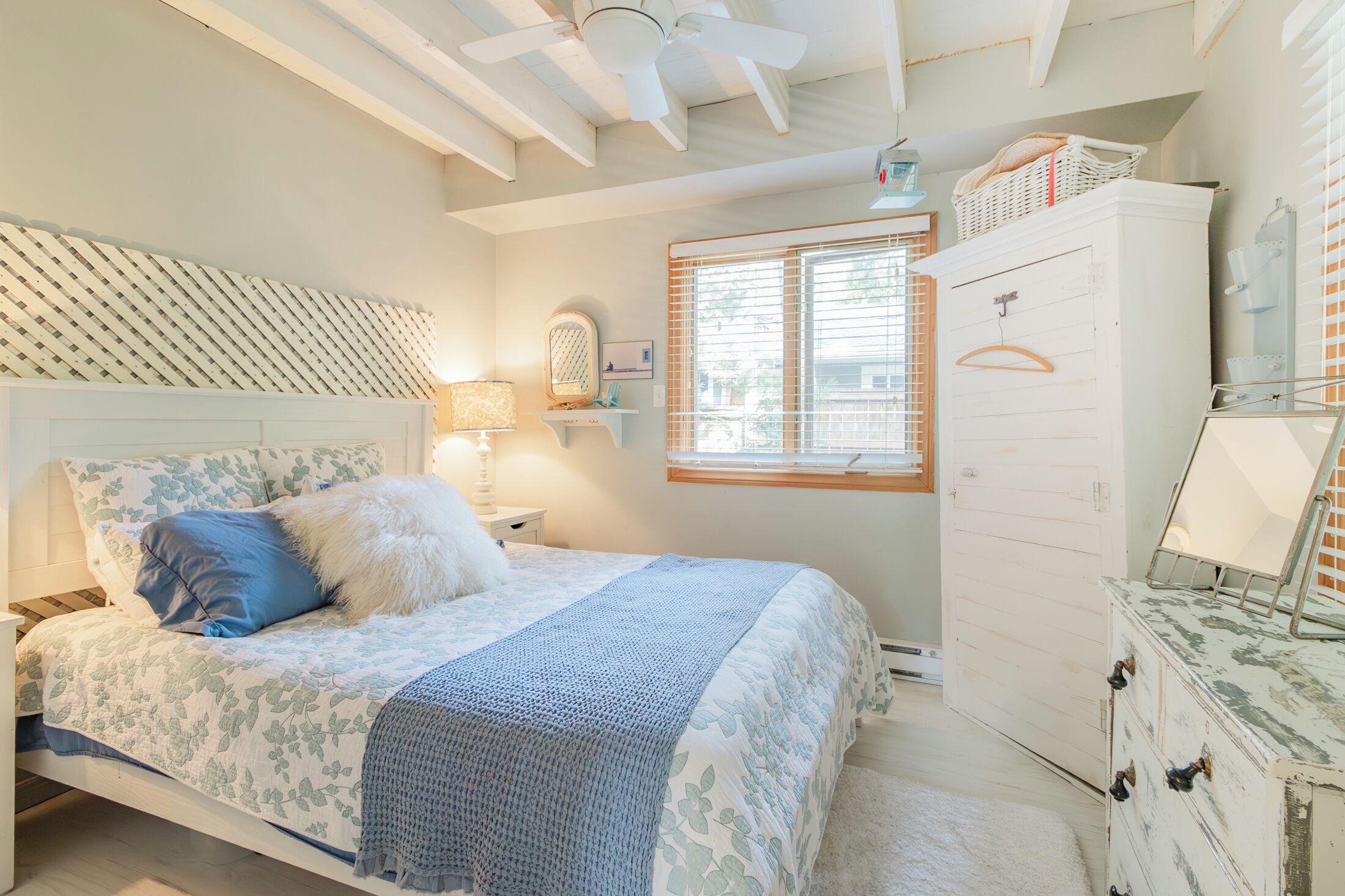 A bedroom with a bed, a dresser, a window, and a ceiling fan.