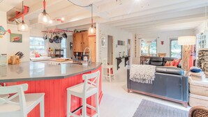 A modern kitchen with a red island, white bar stools, and hanging pots. - Walk to white sand private beach of Oakwood Park - 4 bed cottage steps to lake. (Grand Bend)