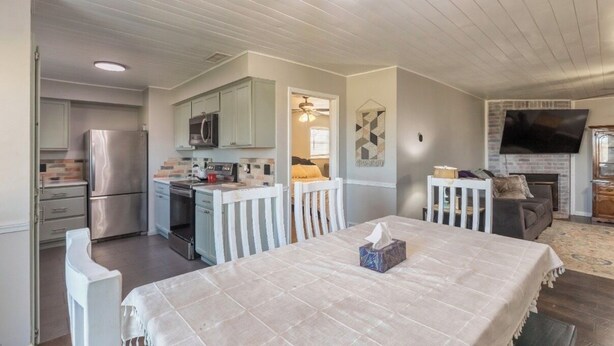 Eine kompakte Küche mit modernen Geräten, ein Essbereich mit Tisch und Stühlen sowie ein Wohnzimmer mit Kamin und Sitzgelegenheiten.