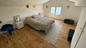 Ein Schlafzimmer mit Bett, Nachttisch, Stuhl, Fenster und Kleiderschrank.