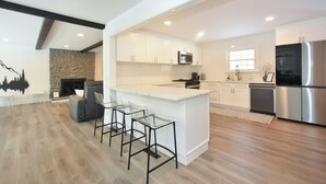 A modern kitchen with white cabinets, a large island, and a built-in oven. - Stream Home (Saratoga Springs)