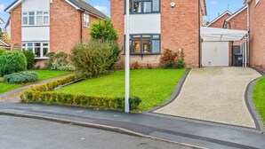 Une maison d’habitation avec un jardin devant, une allée et un garage.