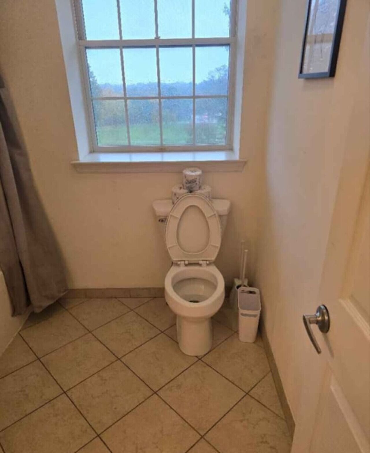 A small bathroom with a toilet, a window, and a door.