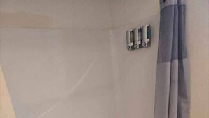 A bathroom with a bathtub, a shower curtain, and a towel rack. - 1BR/1BA Comfortable & Convenient (Belleville)