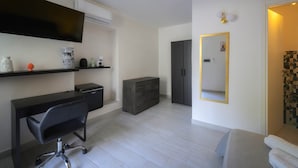 A modern hotel room with a flat-screen TV, a desk, a chair, a dresser, a mirror, and a bed. - La Colombaia Bed and Rooms (Belvedere Marittimo)