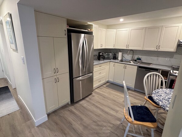 A modern kitchen with stainless steel appliances, light-colored cabinets, and a wooden floor.