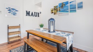 A dining area with a wooden table, bench, and wall-mounted shelf. - Sleeps 12! Ocean Views! 4 BD/4BA! 2 Renovated Condos! (Kihei)