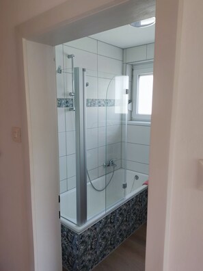 A modern bathroom with a glass-enclosed shower, white tiles, and a patterned tile border. - Variety of lakes: Klopeiner See, Gösselsdorfer See, Turner See. (Sittersdorf)