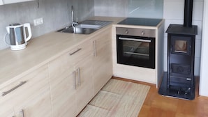 A modern kitchen with light wood cabinets, a built-in oven, a black stove, and a stainless steel sink. - Variety of lakes: Klopeiner See, Gösselsdorfer See, Turner See. (Sittersdorf)