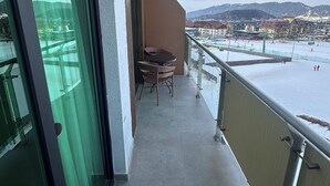 Ein Balkon mit Blick auf eine verschneite Landschaft und Gebäude.