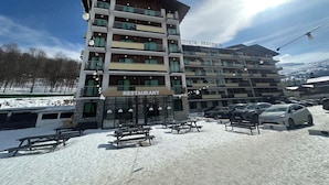 Ein mehrstöckiges Hotel mit Restaurant im Erdgeschoss, Außenbereich und Blick auf schneebedeckte Berge.