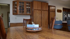A wooden dining table with a cake centerpiece, wooden cabinets, and blue chairs.
