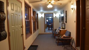 A hallway with a ceiling fan, a door, and a chair with a small table.