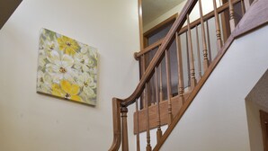 A wooden staircase with a handrail, carpeted steps, and a ceiling light.