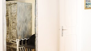 Et værelse med en hvid dør, et spejl der viser en trækonstruktion, og et billede i ramme på væggen.