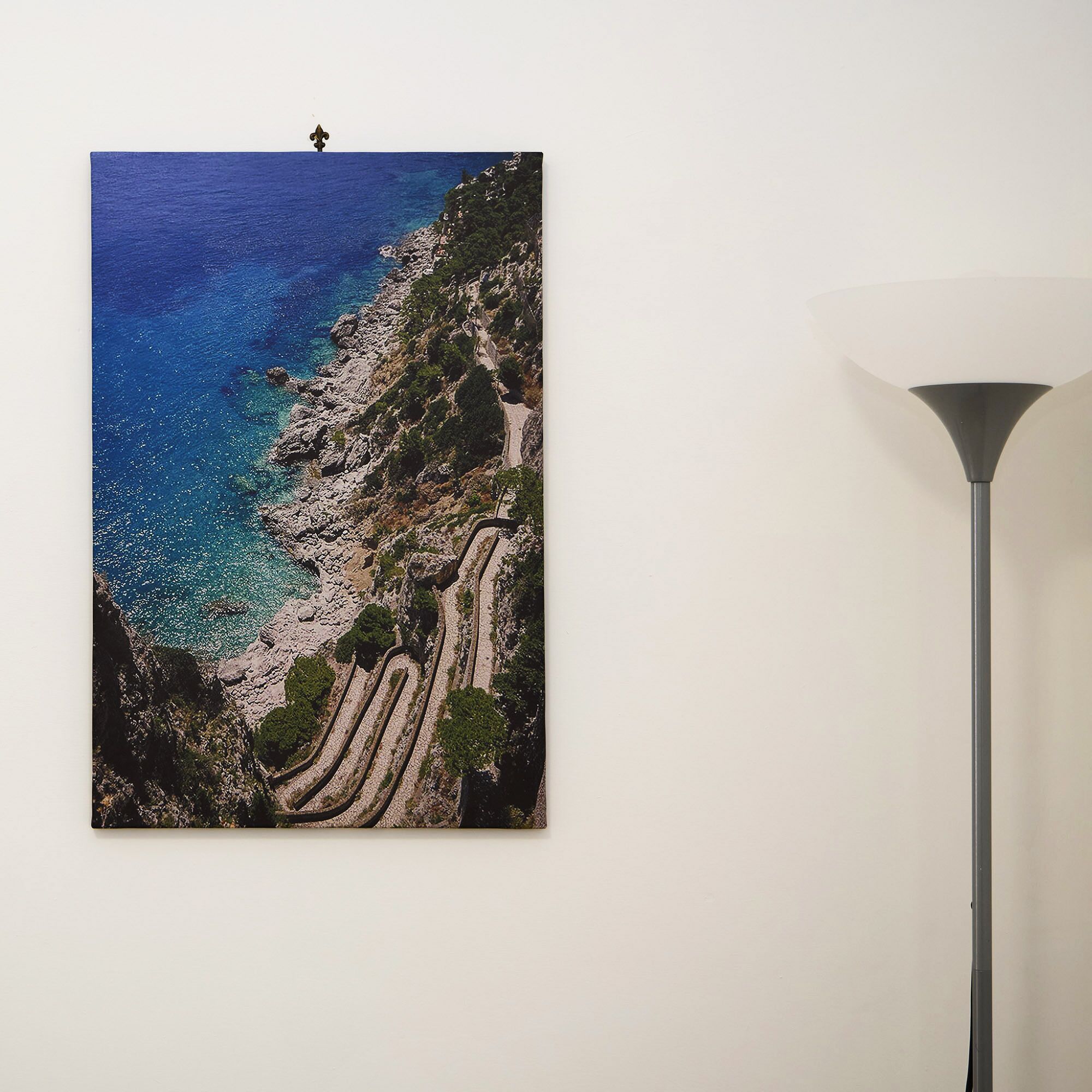 Un tableau représentant un paysage côtier, avec un ciel dégagé, un terrain rocheux et un sentier sinueux.