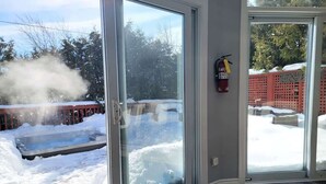 A glass door leading to a snowy outdoor area with a fire extinguisher mounted on the wall. - Private Ski Chalet Hot Tub & Mountain Views (The Blue Mountains)