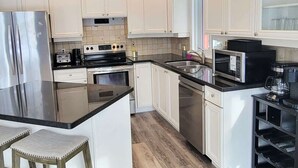 A modern kitchen with white cabinets, stainless steel appliances, and a wooden floor. - Private Ski Chalet Hot Tub & Mountain Views (The Blue Mountains)