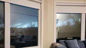 A room with a large window, a grey sectional sofa, and a wooden floor. - Private Ski Chalet Hot Tub & Mountain Views (The Blue Mountains)