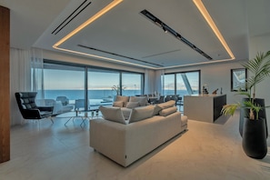 Ein modernes Wohnzimmer mit einer großen Couch, einem Essbereich und Meerblick.