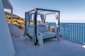 Ein Balkon mit einem Bett, einem kleinen Tisch und Blick auf das Meer.