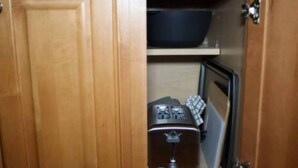 A wooden cabinet with a black bowl on top, a small electronic device, and a keyboard. - Stylish 1BR Apartment Prime Location (Belleville)