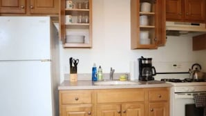 A kitchen with wooden cabinets, a refrigerator, a stove, and a sink. - Stylish 1BR Apartment Prime Location (Belleville)