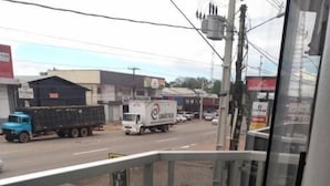 A balcony with a metal railing overlooking a street with vehicles and buildings. - HOTEL NOVAES (Castanhal)