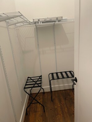 A storage closet with metal shelving units and two black drying racks.