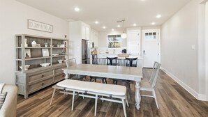 Une cuisine spacieuse dotée d’un îlot central, de meubles blancs et d’un coin repas avec une banquette.