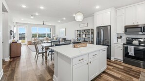 Une cuisine moderne avec des meubles blancs, des appareils en acier inoxydable et un grand îlot central.
