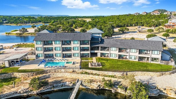 Un hôtel à plusieurs étages doté d’une piscine, d’un espace extérieur aménagé et offrant une vue sur un lac et des collines.