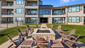 Un immeuble à plusieurs étages doté d’une terrasse et d’un foyer extérieur.