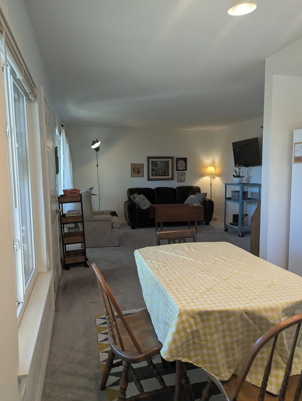 Un salon confortable avec un canapé, une table basse, un téléviseur et un coin repas comprenant des chaises et une table.