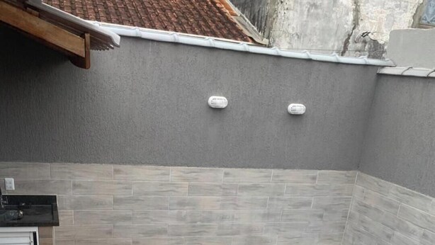 Ein rechteckiger Pool mit einer Fliesenleiste, umgeben von einer grauen Wand mit einem gefliesten unteren Bereich und einem weißen oberen Bereich.