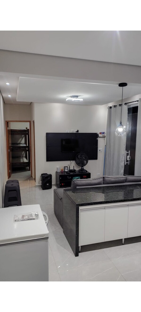 Een moderne keuken met een ingebouwde kookplaat, een eettafel en een grote flatscreen televisie aan de muur.