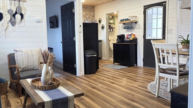 Un vaste espace de vie doté d’un plancher en bois, d’un ventilateur de plafond et d’un coin repas avec une table et des chaises.