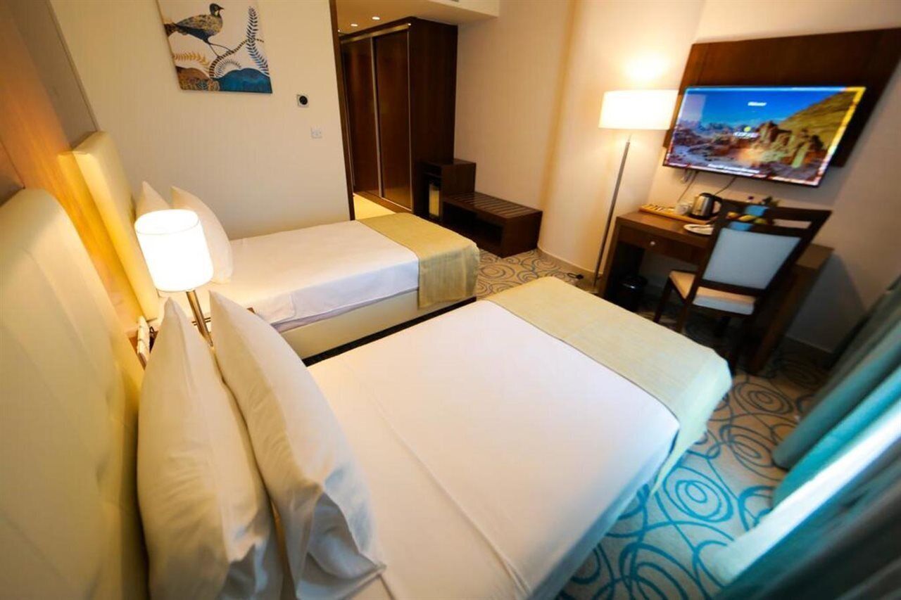Habitación de hotel con dos camas, un escritorio, un televisor y un armario.
